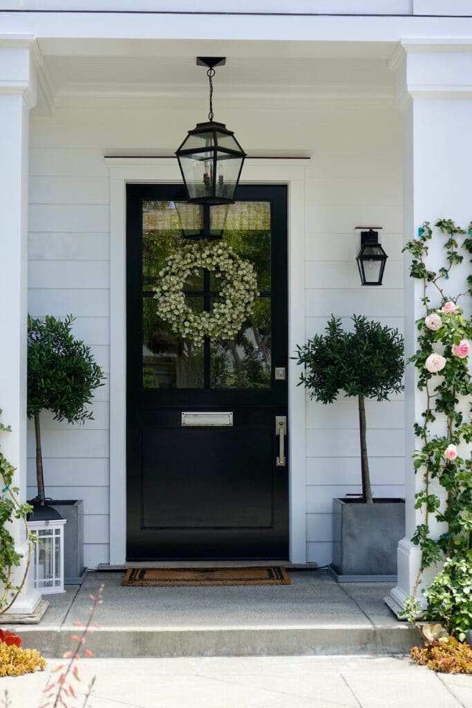 A front porch with two topiary planters on either side of the front door.
